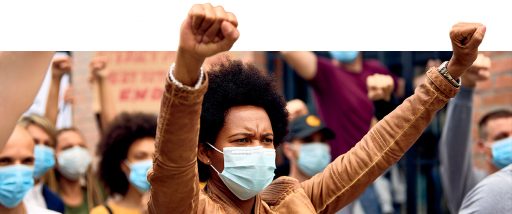 Black woman with medical mask raises both fists in triumph